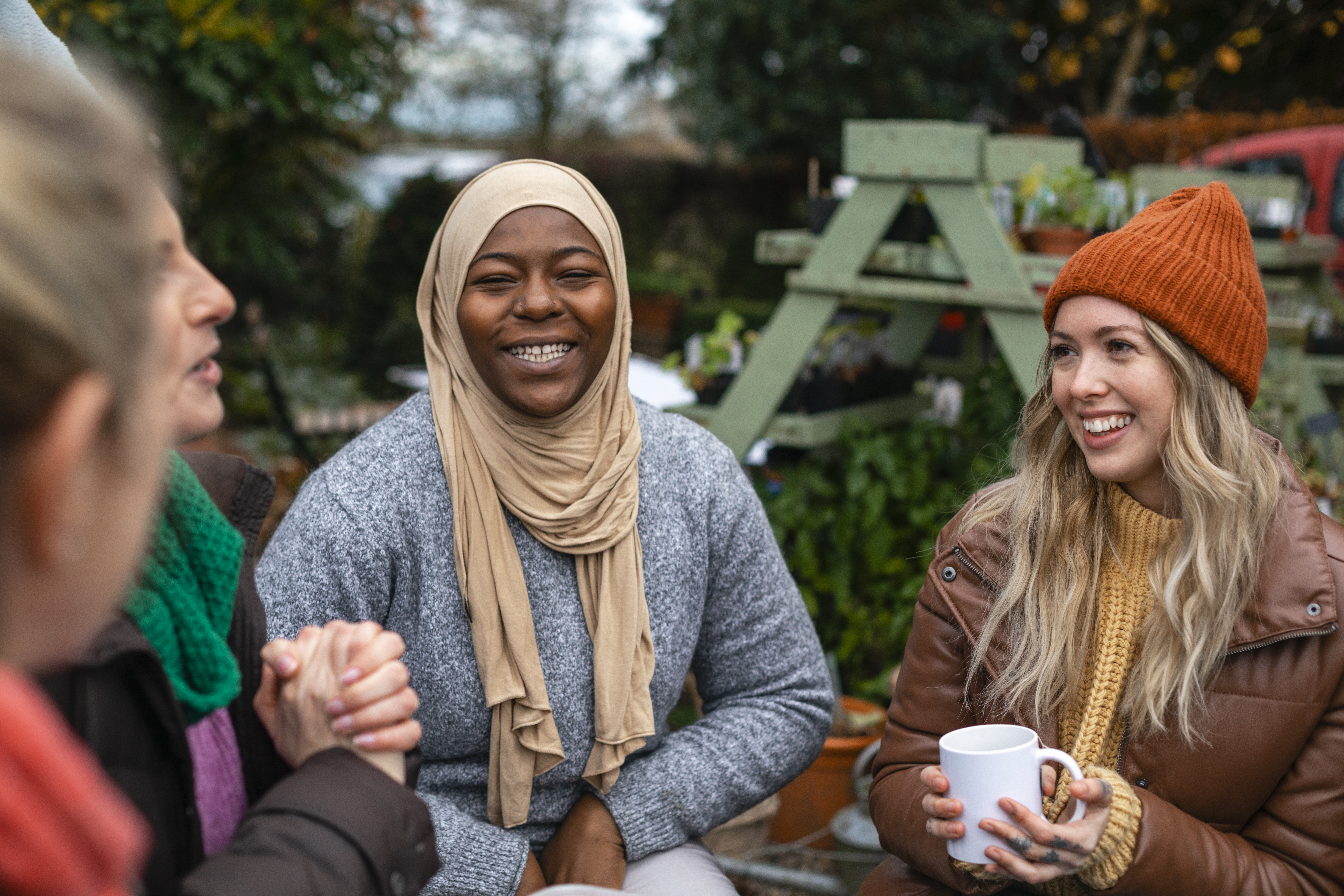 A group of people sit outside talking and smiling