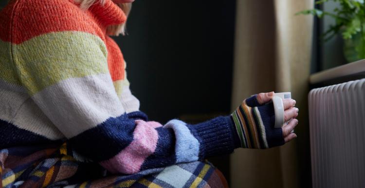 An arm wearing a stripy jumper, holding a mug