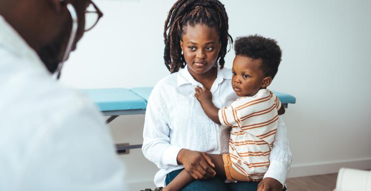A woman and a baby sitting down, with a GP talking to them