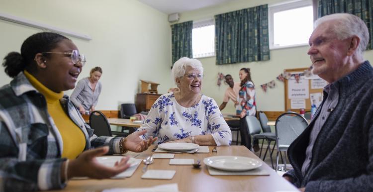 A group of elderly people sitting around a table talking