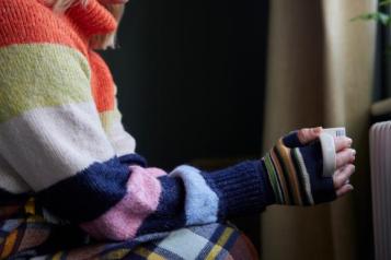 An arm wearing a stripy jumper, holding a mug