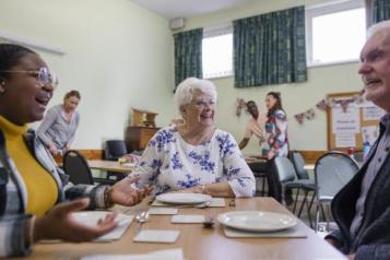 A group of elderly people sitting around a table talking