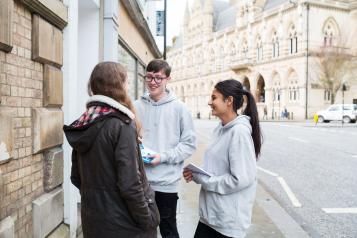 Two teenage Healthwatch volunteers talking to a member of the public about their experience