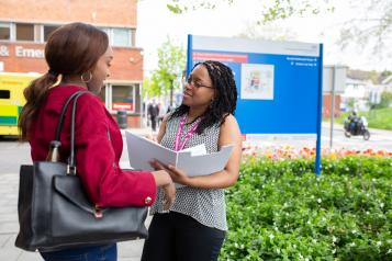 two women talking outside hospital entrance