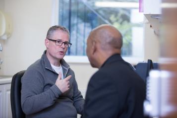 Man sitting in a GP consulting room talking to his male doctor