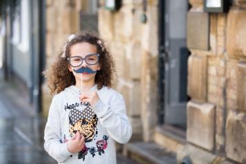 Small child holding up mustache prop for a photograph
