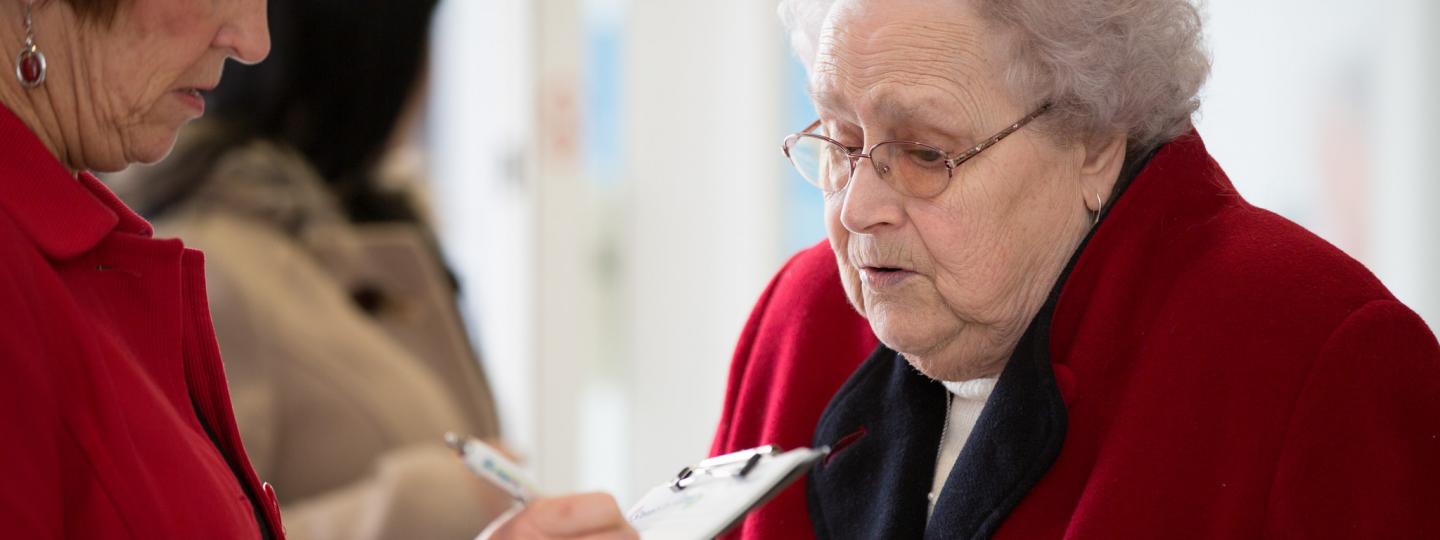 Elderly lady talking to someone with a clipboard