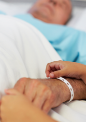 man lying down in a hospital bed with a child holding his hand